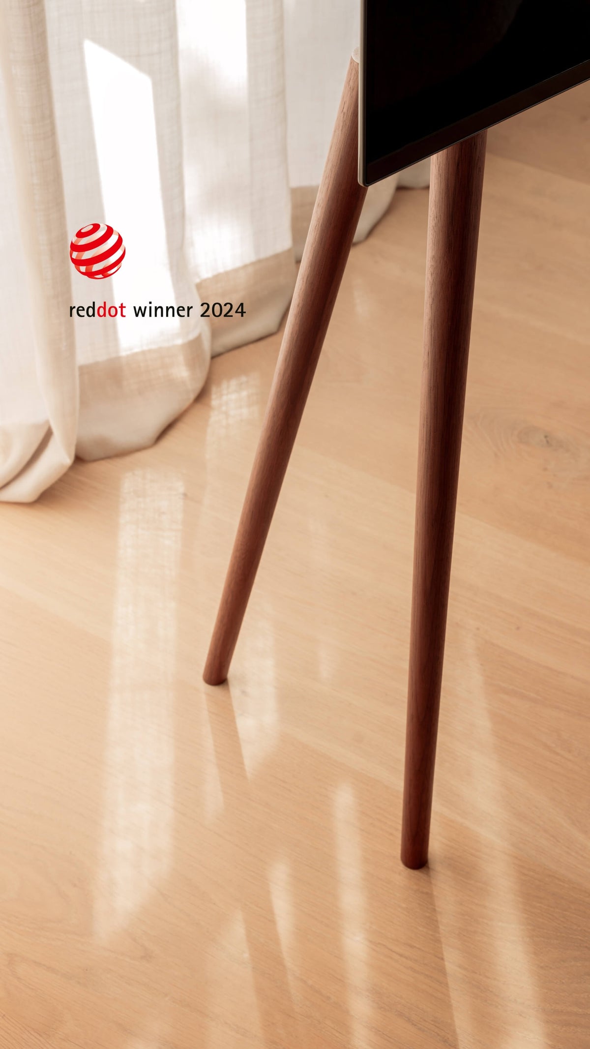 A close-up of freestanding JALG TV stand with tapered dark wood legs, Red Dot Winner 2024, mobile layout