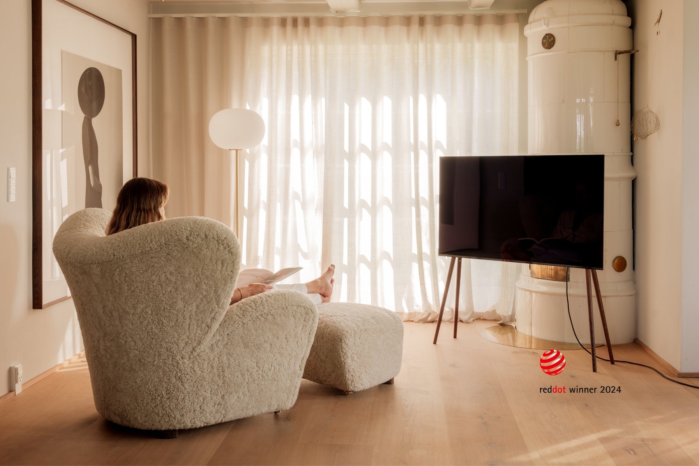 Freestanding JALG TV stand and a woman reading in front of the TV, Red Dot Winner 2024, mobile layout