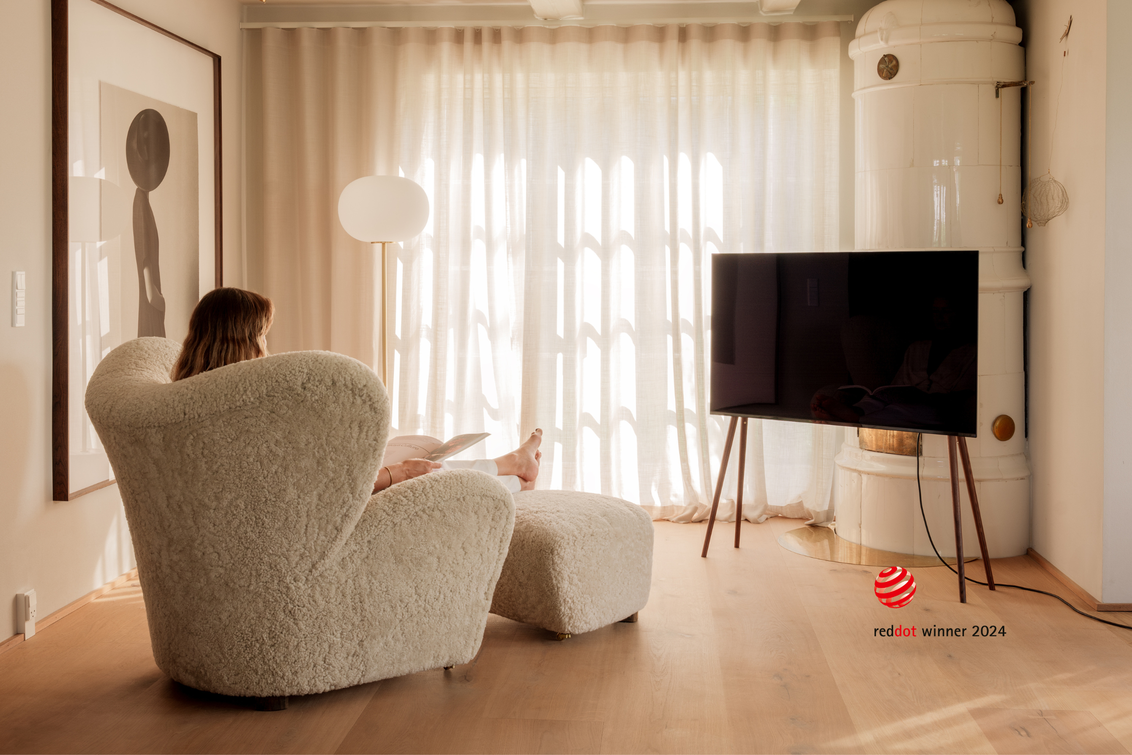 Freestanding JALG TV stand and a woman reading in front of the TV, Red Dot Winner 2024, mobile layout
